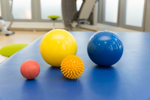 Nahaufnahme verschiedener Gymnastik- und Massagebälle auf einer blauen Matte.